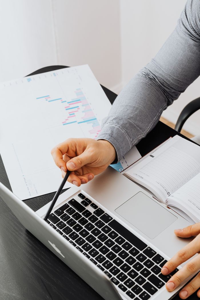 Business professional analyzing charts and data on a laptop in office setting.