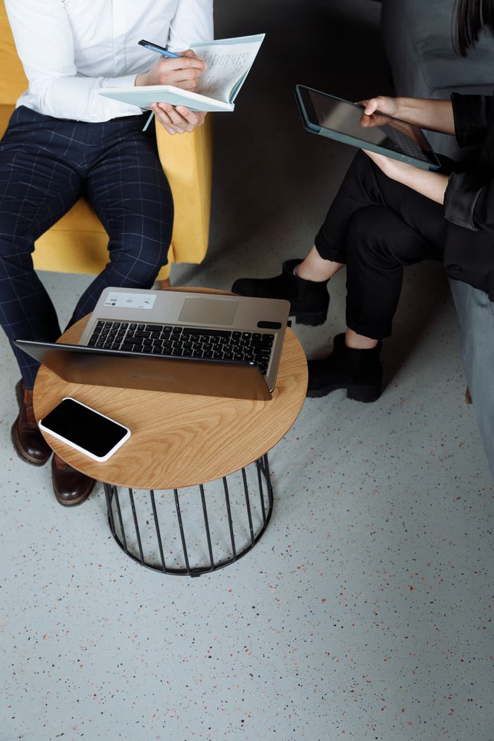 Adults collaborating in an office using laptop and tablet, emphasizing teamwork and digital tools.